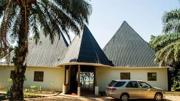 A building with a unique pyramid-shaped roof, a car parked in front, and a palm tree nearby.