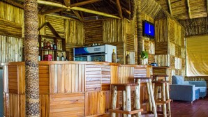 A rustic wooden bar area with a minibar, stools, and a television.