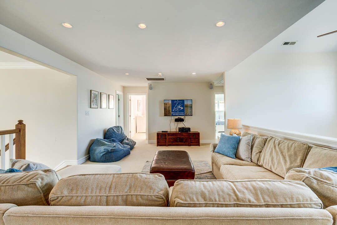 A spacious living room with a beige sofa set, a blue bean bag, and a wooden coffee table.