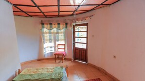 A room with a bed, a chair, a window with curtains, and a door. - Hakurya Gasabo Lodge (Kigali)