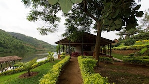 A covered pavilion with a dirt path leading to it, surrounded by well-maintained greenery and a lake. - Hakurya Gasabo Lodge (Kigali)