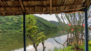 A wooden gazebo overlooking a calm lake with lush greenery and a wooden deck. - Hakurya Gasabo Lodge (Kigali)