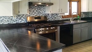 A kitchen with a stainless steel stove, a dishwasher, and a sink.