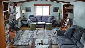 A cozy living room with a grey sofa, a coffee table, and a bookshelf.
