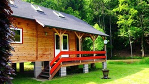 Een houten chalet met een veranda en een trap naar de ingang.