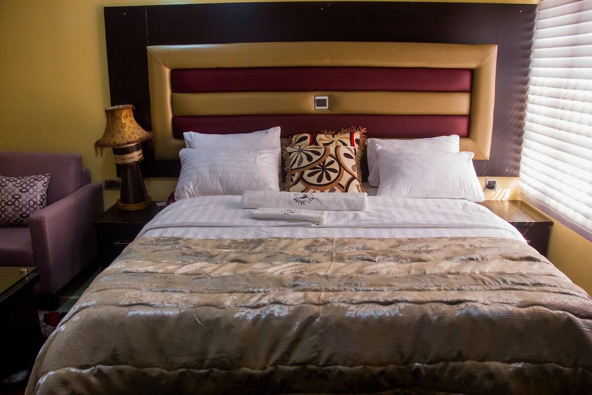 A hotel room with a large bed, two bedside tables, a lamp, and a chair.