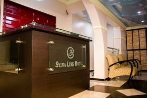 A reception desk with a glass top and a wooden base, labeled "Sylva Link Hotel." - Sylva Link Suites (Lekki)