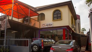 A building with a sign for 'Aivilos Kitchen' and parked cars in front. - Sylva Link Suites (Lekki)