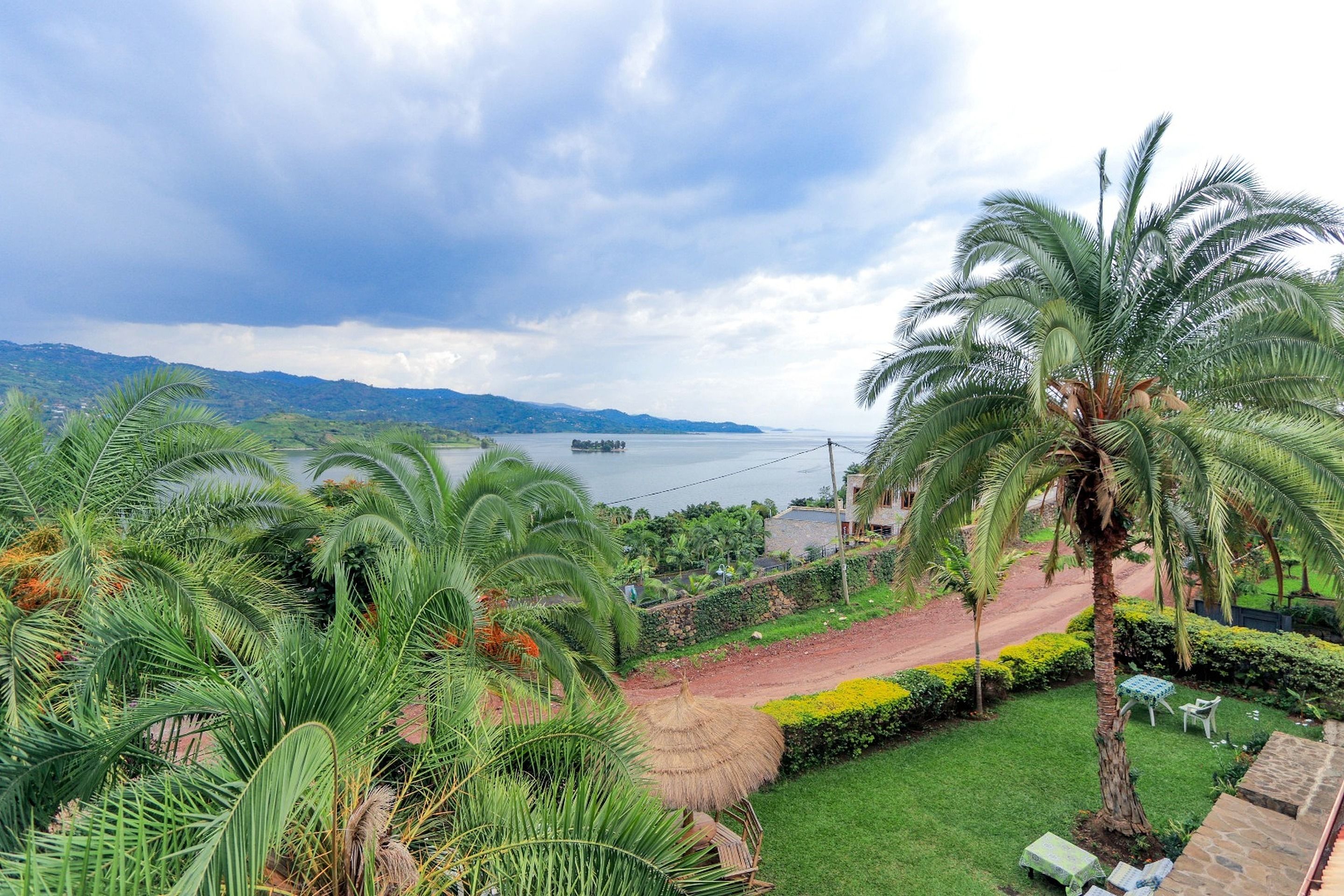 Un resort tropical con vistas al mar, palmeras y una estructura de techo de paja.