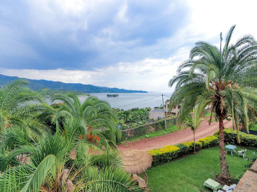 Un complexe hôtelier tropical offrant une vue sur la mer, des palmiers et une structure surmontée d’un toit de chaume.