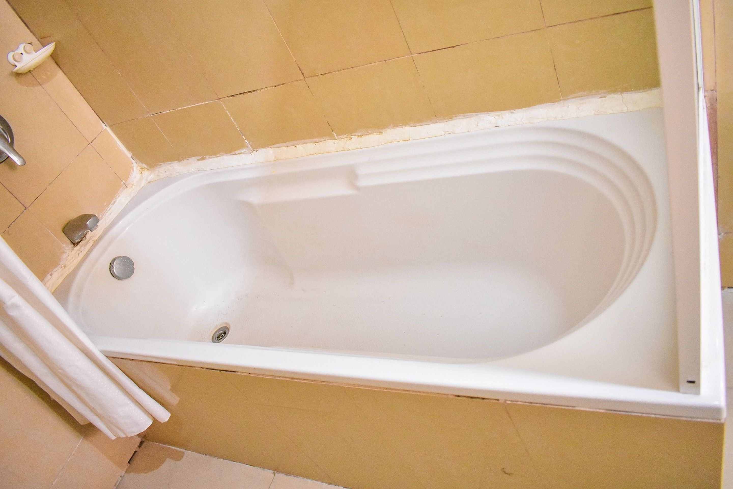A bathtub with a drain, a shower curtain, and a towel rack.