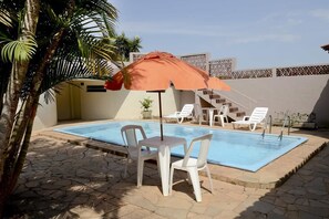 Una piscina al aire libre, sillones reclinables de piscina