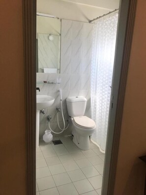 Et badeværelse med toilet, håndvask og bruseområde.