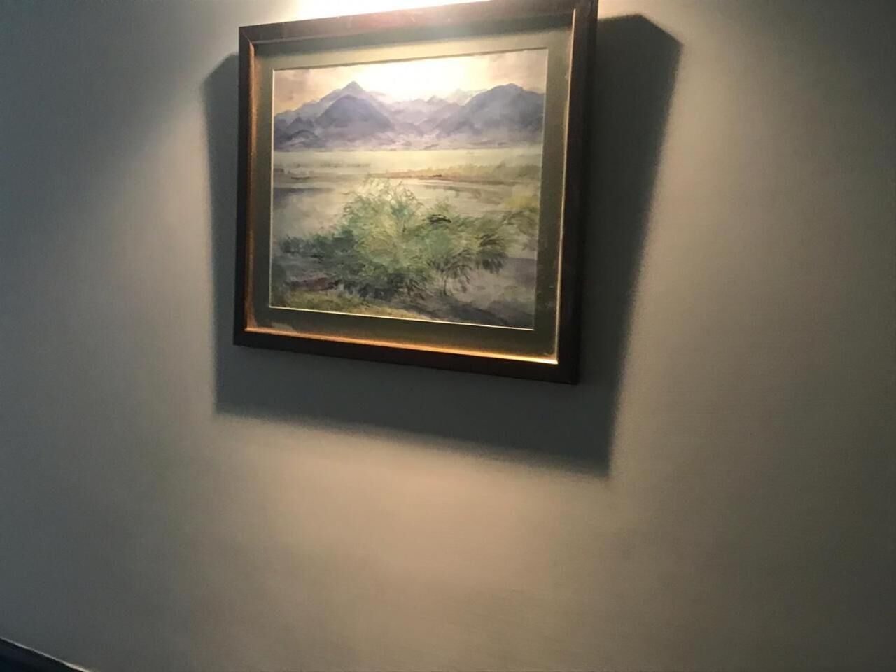 A framed landscape painting on a wall.