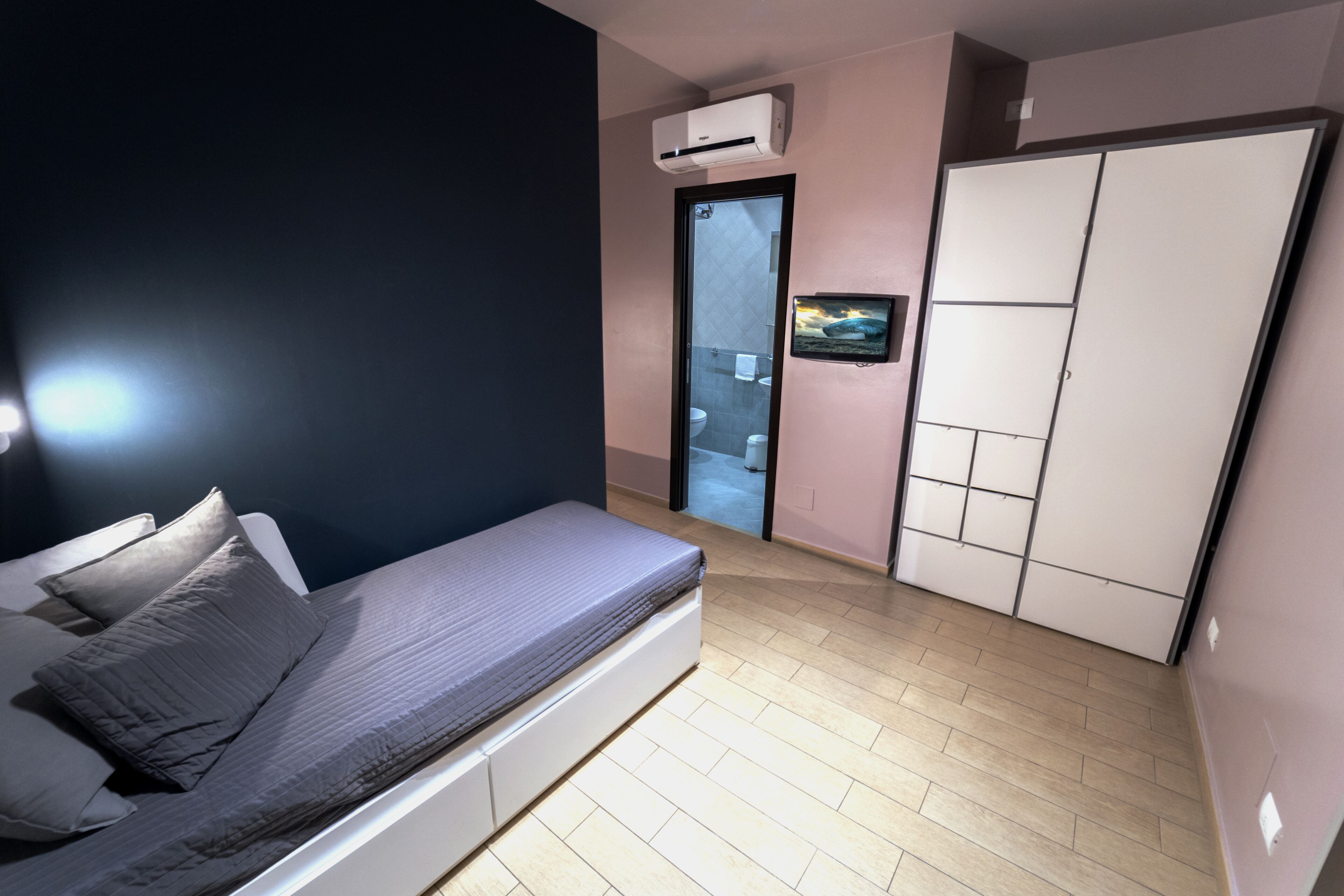 Ein Schlafzimmer mit Bett, Kleiderschrank, Klimaanlage und Fernseher an der Wand.