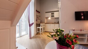 A modern kitchen with white cabinets, a dining area with a table and chairs, and a TV mounted on the wall. - Relais al Museo (Naples)