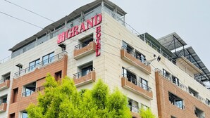 A multi-story hotel with a prominent "GRAND HOTEL" sign, balconies, and a mix of brick and concrete exterior.
