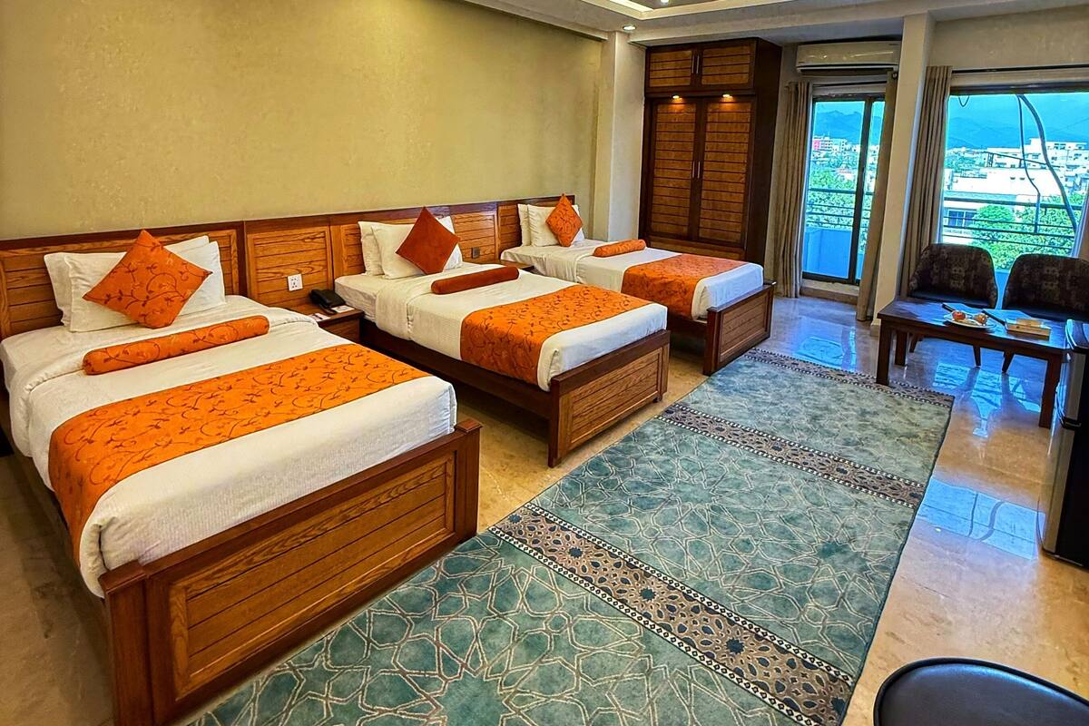 Een hotelkamer met drie bedden, een slaapbank en een eethoek.