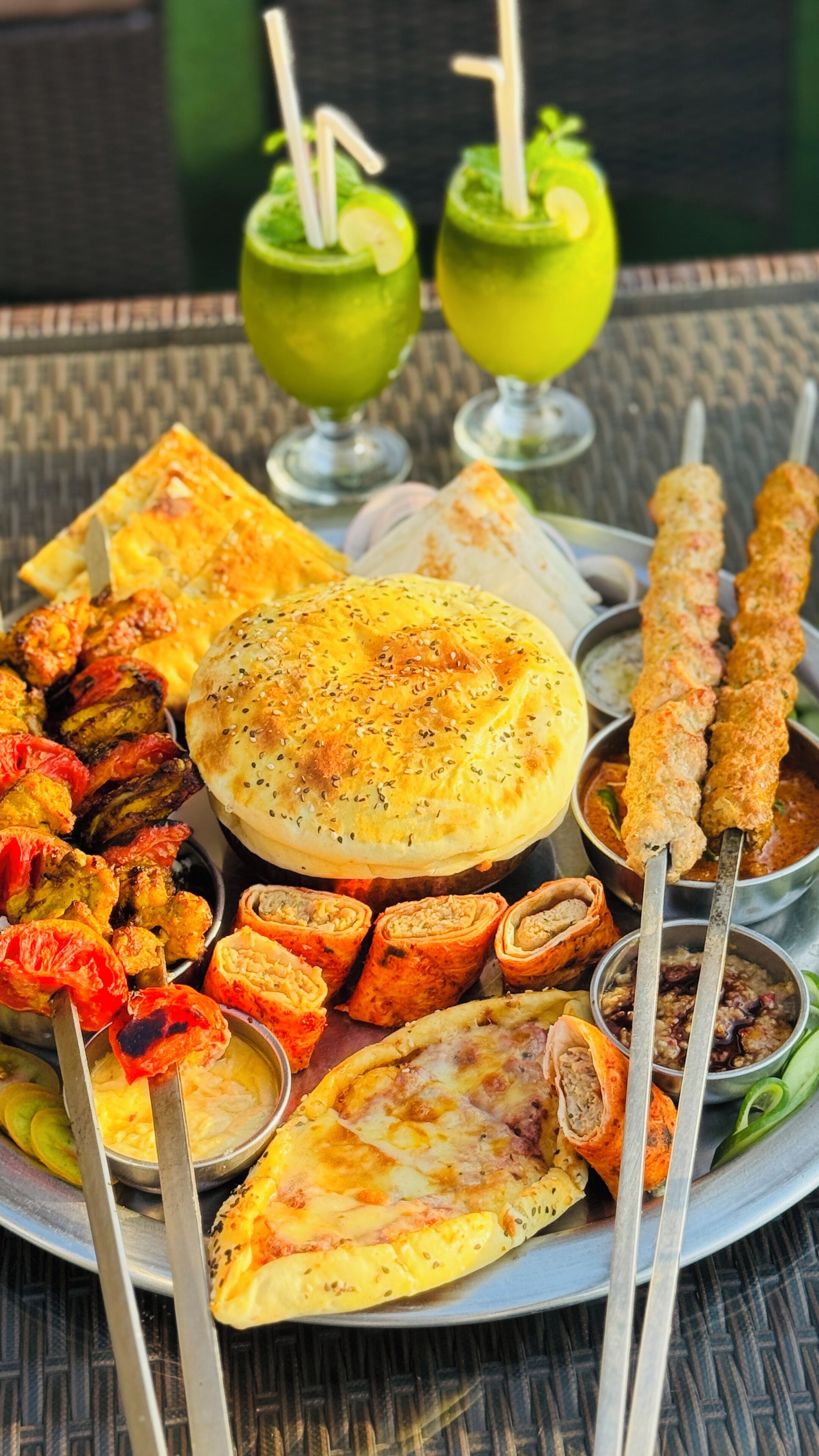 Diversos pratos de comida, incluindo kebabs, pães sírios e um prato com legumes fatiados.