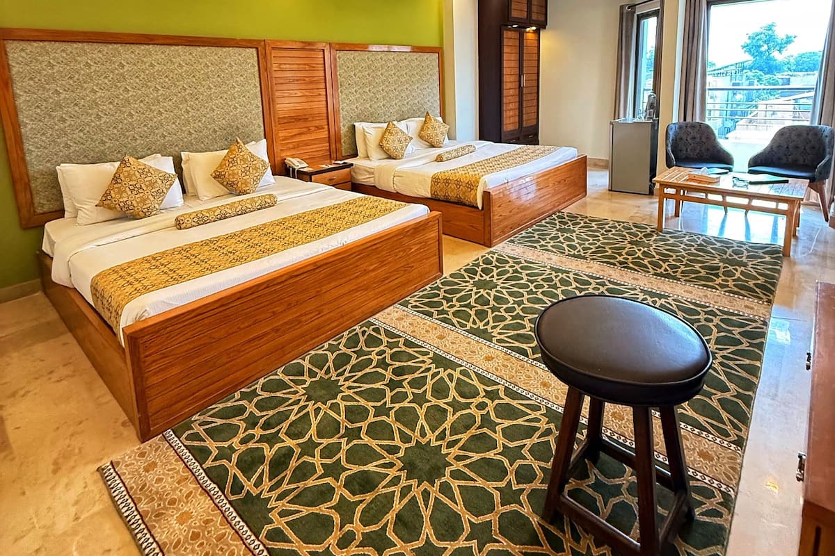 Een hotelkamer met twee bedden, een zithoek en uitzicht op de omgeving.