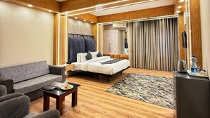 A modern hotel room with a sofa, a bed, a coffee table, and a small desk.