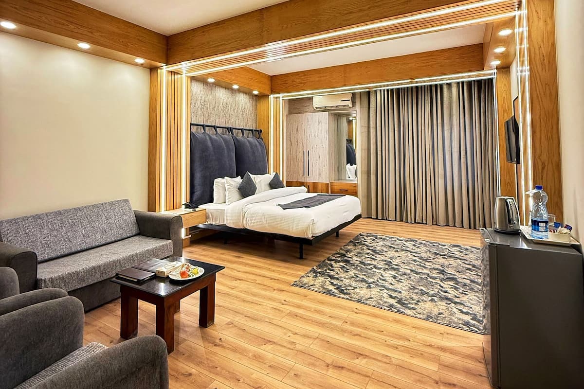 Een moderne hotelkamer met een bank, een bed, een salontafel en een klein bureau.