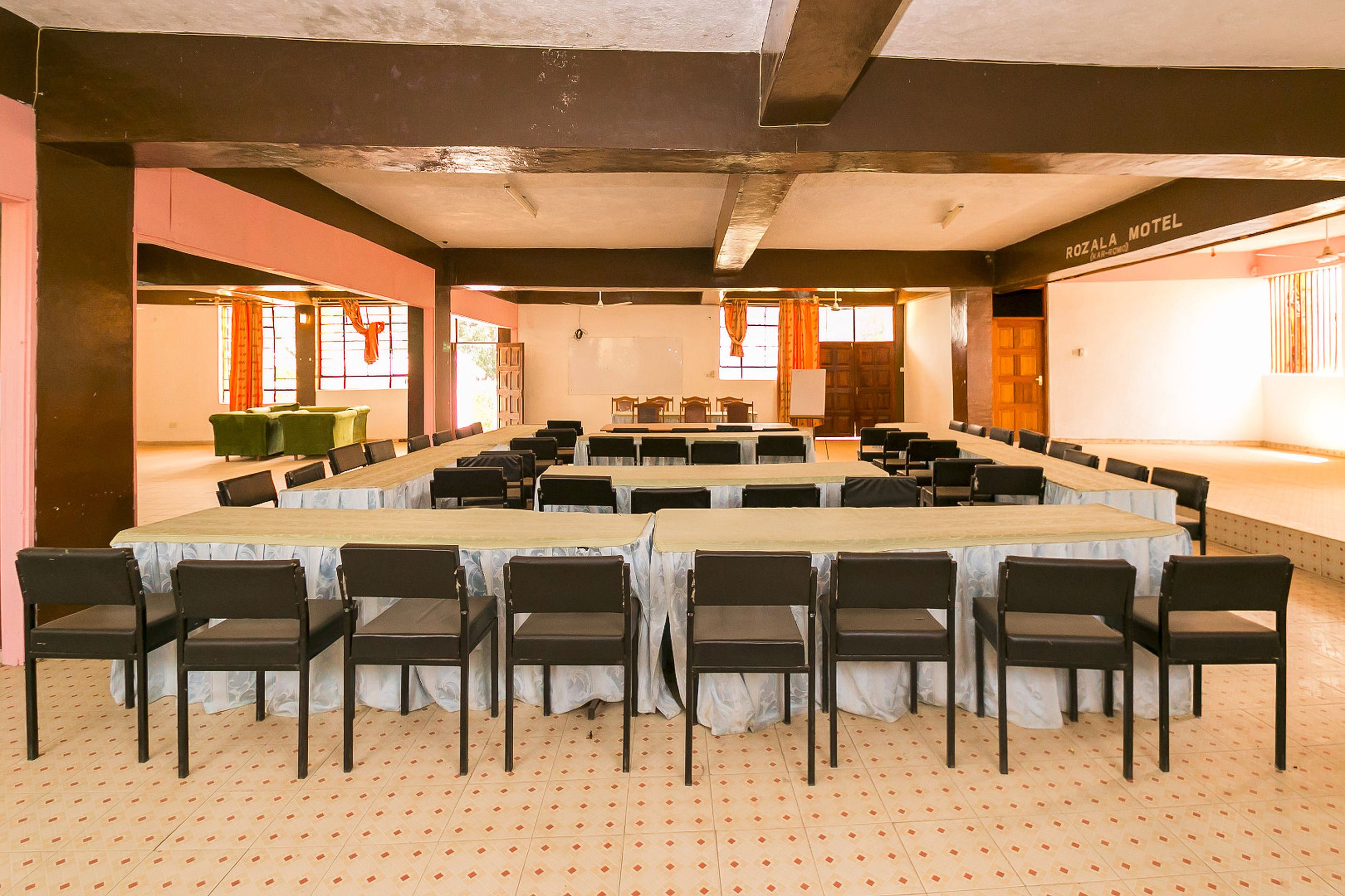 Un salón de conferencias con una gran mesa y sillas, una pizarra y un letrero que dice "ROZALA MOTEL".