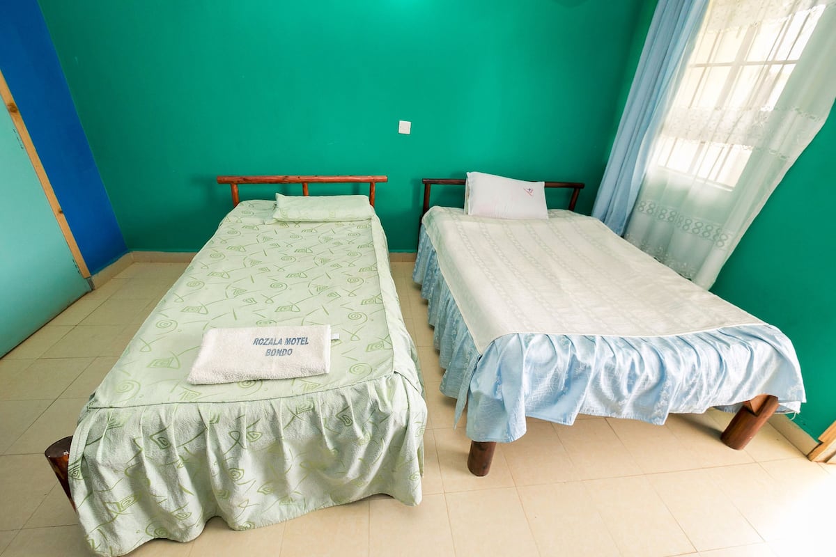 Two single beds in a room with teal walls, each with a different patterned bedspread.