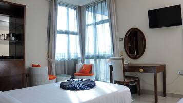 A hotel room with a bed, a desk, a chair, a television, and a large window with curtains.