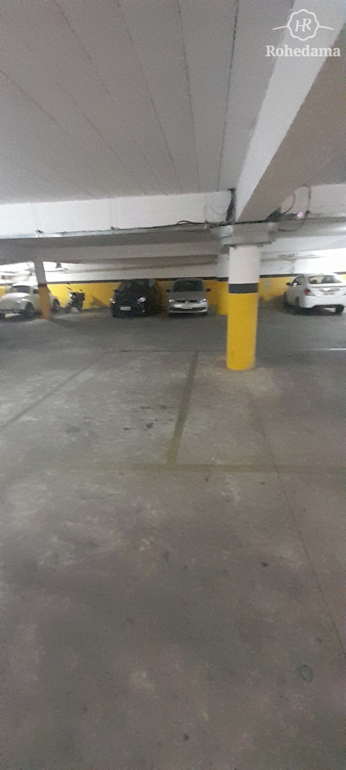 Een ondergrondse parkeerruimte met betonnen vloeren en gele pilaren.