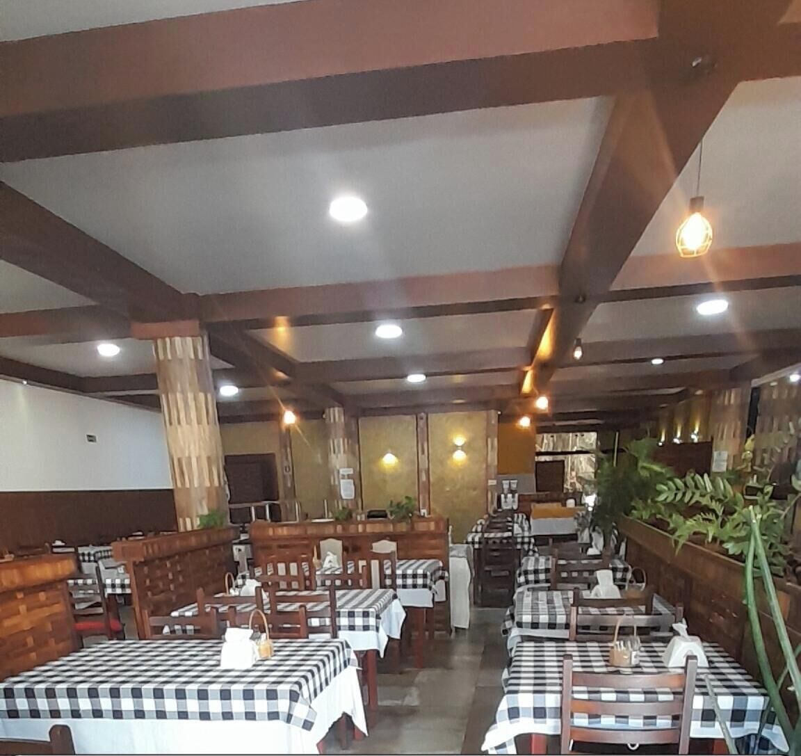 Un restaurant avec des nappes à carreaux, des chaises en bois et des luminaires suspendus.