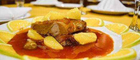 A plate of food with meat and pineapple on a white plate, surrounded by lime slices.