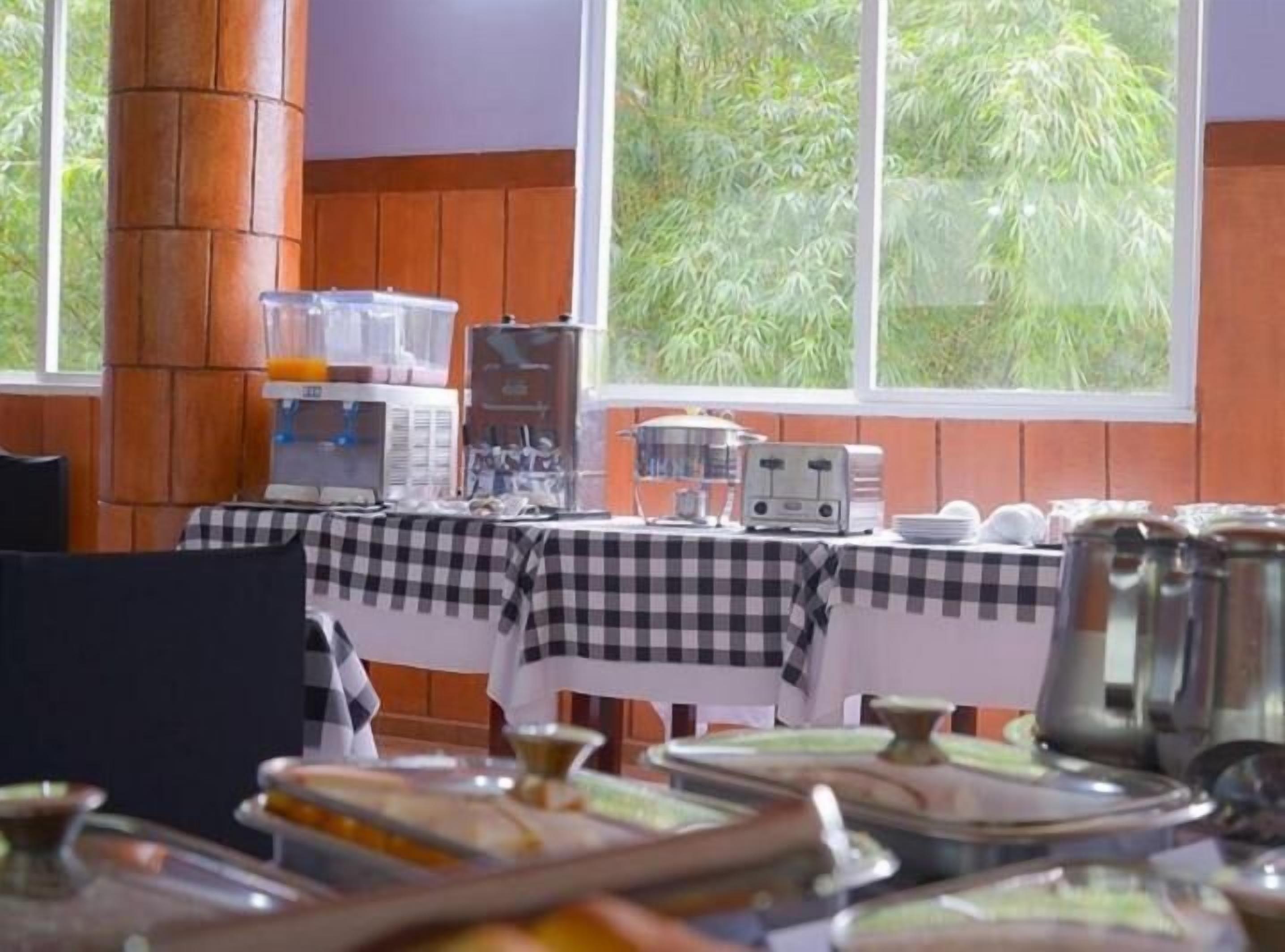 Een ontbijtarrangement met een geruit tafelkleed, een koffiezetapparaat en diverse ontbijtbestekken.