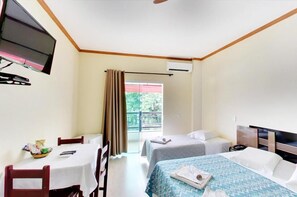 Une chambre d’hôtel avec deux lits, une télévision, une table avec des chaises et un balcon avec des rideaux.