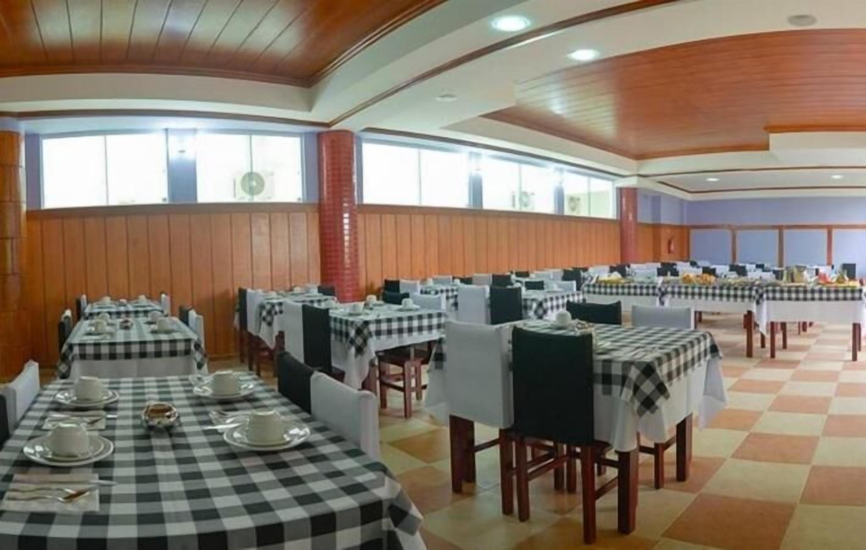 A large dining hall with checkered tablecloths, wooden paneling, and a high ceiling.