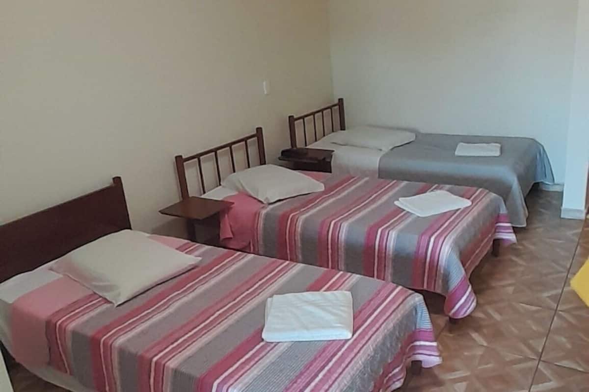 A hotel room with two beds, a wooden headboard, a small table, and a patterned floor.