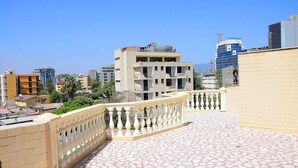 A rooftop terrace with a patterned floor, a decorative railing, and a view of surrounding buildings. - Grand Guest House (Addis Ababa)