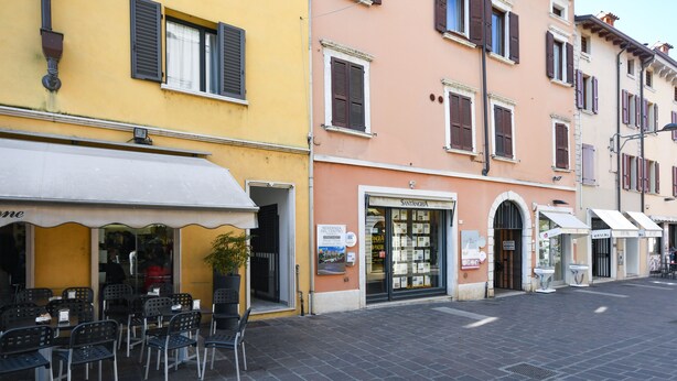 A street with outdoor seating and a storefront with a sign that reads "SANTANZA." - Desenzanoloft – Desenzano Corte Blu Downtown (Desenzano del Garda)