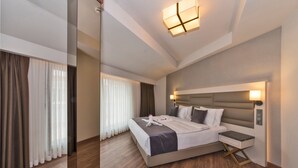 A modern hotel room with a large bed, bedside tables, and a ceiling light fixture. - Golden Royal Hotel & Spa (Istanbul)