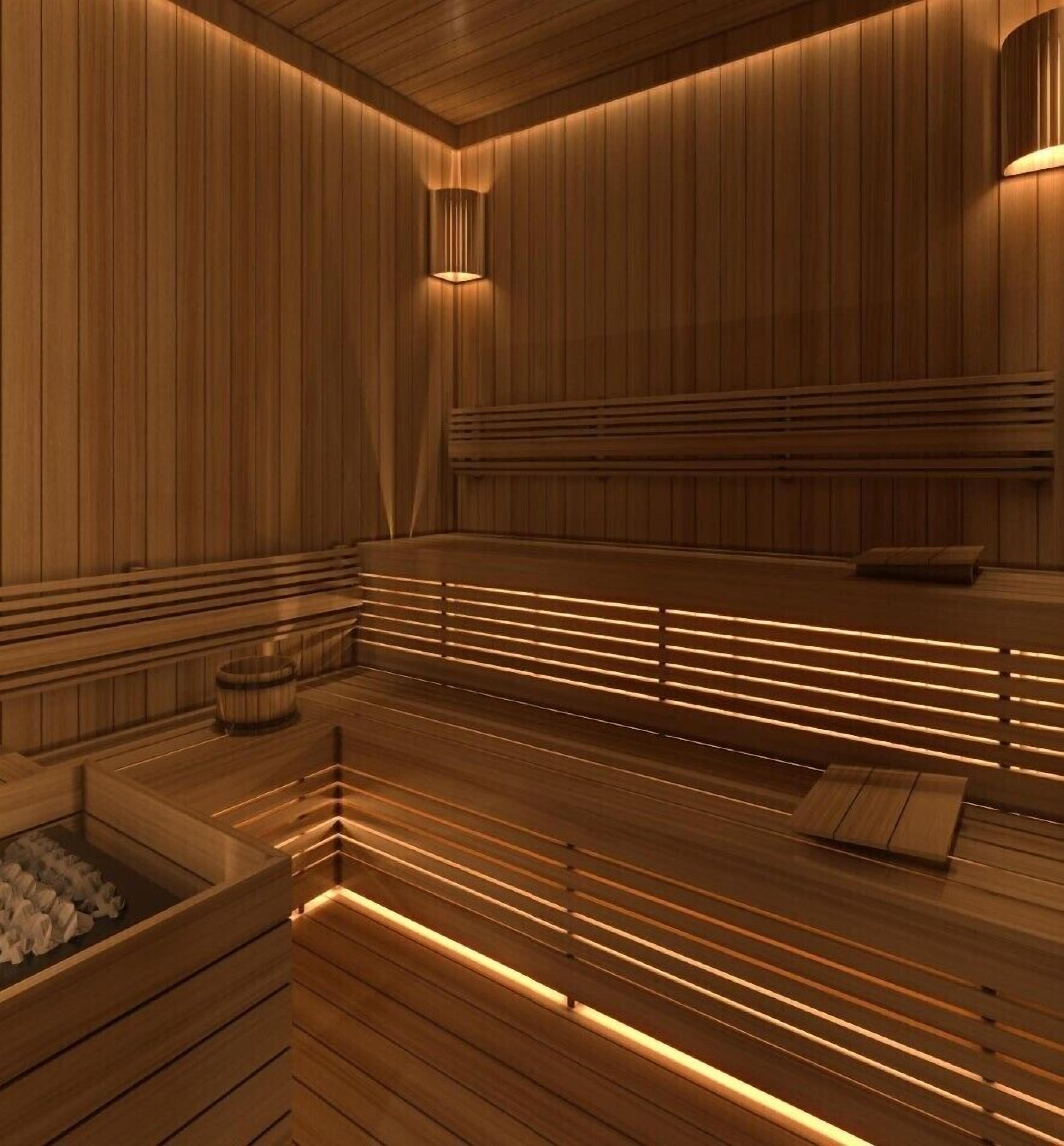 A sauna with wooden benches and a bench seat, a wooden floor, and a wall-mounted light fixture.
