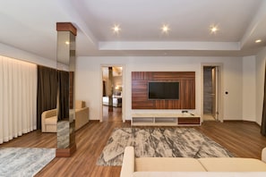 Uma sala de estar moderna com uma grande TV de tela plana, painel de parede de madeira e um espelho grande.