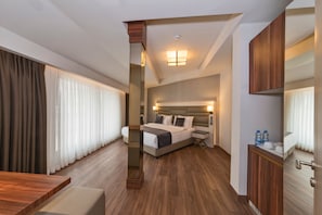 Quarto de hotel com uma cama grande, uma escrivaninha e um espelho.
