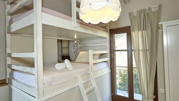 A bunk bed room with a ladder, a window with curtains, and a door.