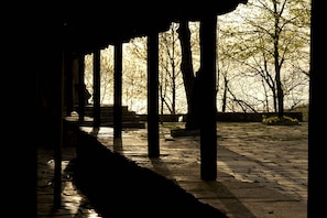 A covered outdoor area with stone flooring and columns, surrounded by trees. - Villa Thea (Zagora-Mouresi)