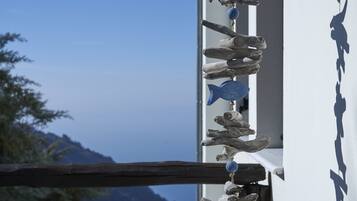 A wooden structure with a blue fish ornament, a mountain view, and a shadow on a wall.