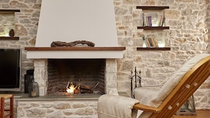 Una chimenea de piedra con un televisor y estanterías arriba.