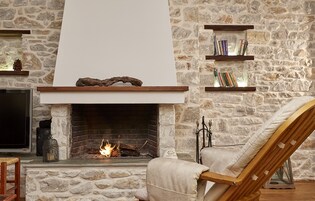 Una chimenea de piedra con un televisor y estanterías arriba.