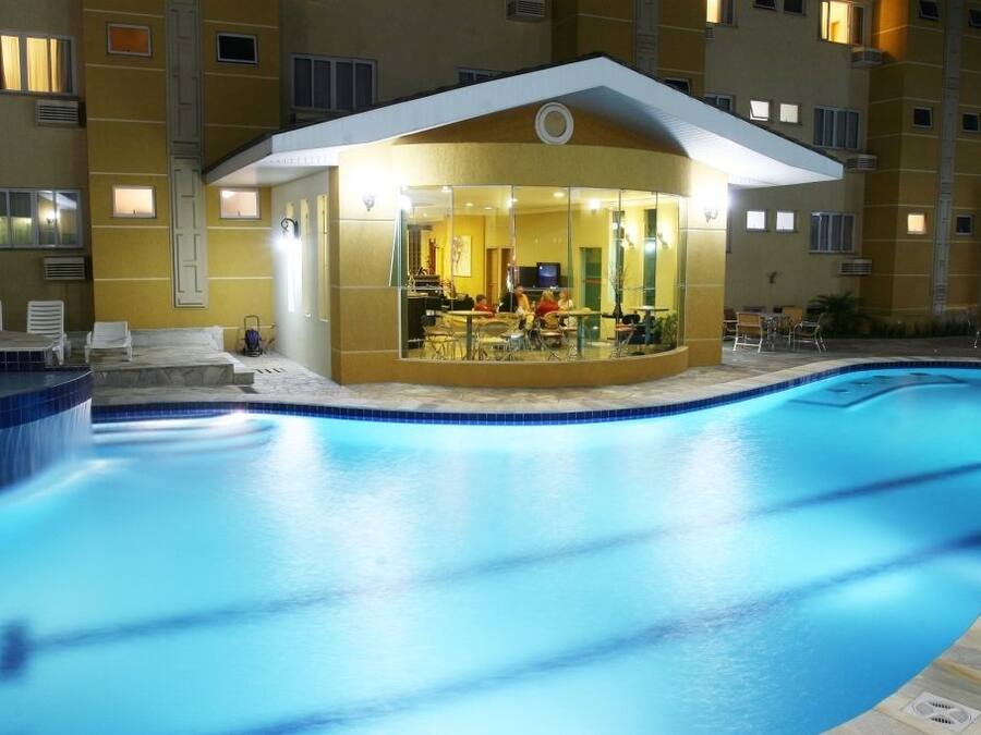 A hotel with a swimming pool, a covered outdoor dining area, and a building with multiple windows.