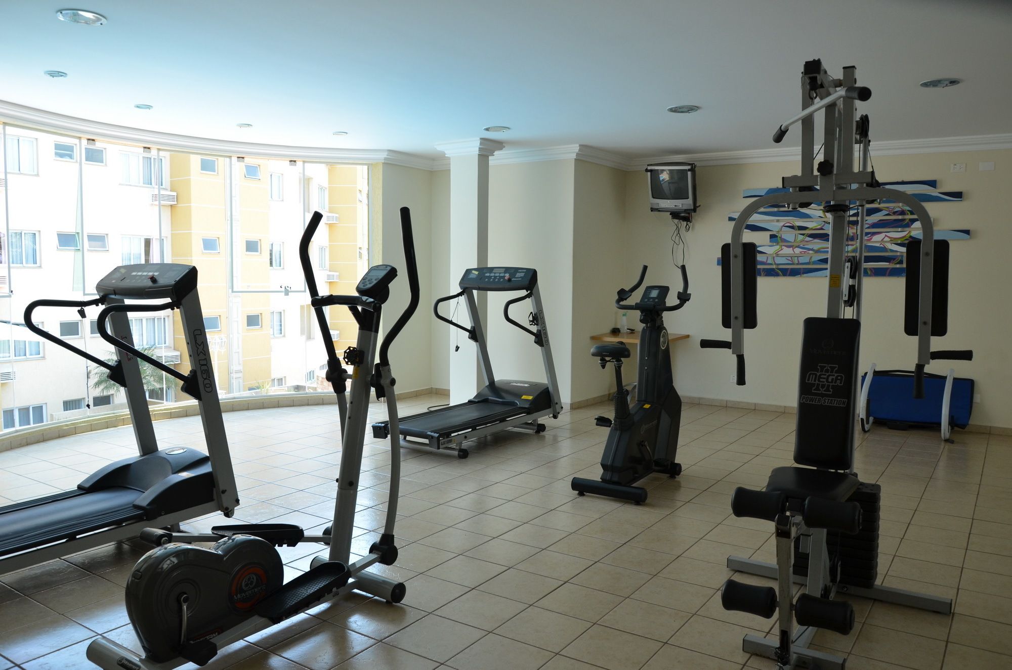 A gym with treadmills, elliptical machines, a power station, and weight benches.
