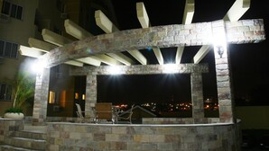 Un área de bar al aire libre con paredes de piedra y una estructura de pérgola.